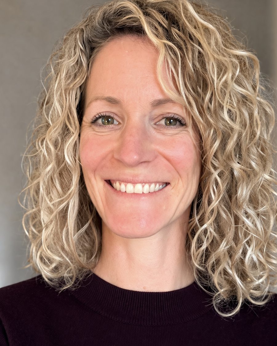 Portrait de Laure Hambenne, souriante, cheveux blonds bouclés, pull bordeaux